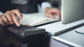 Donna che effettua calcoli con calcolatrice e computer