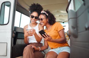 Ragazze in vacanza che usano il telefono Ragazze in vacanza che usano il telefono