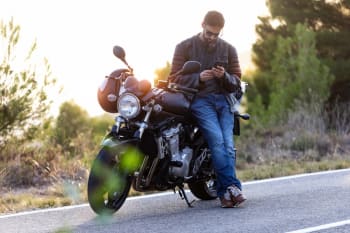 uomo al telefono seduto sulla sua moto