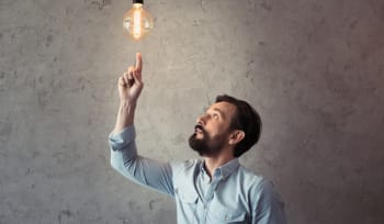 uomo che punta alla lampadina illuminata