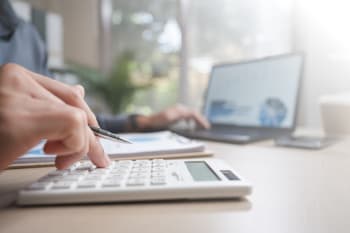 uomo digita su calcolatrice e pc uomo digita su calcolatrice e pc
