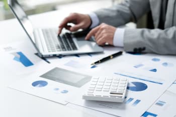 uomo usa la calcolatrice insieme al pc e fogli di lavoro