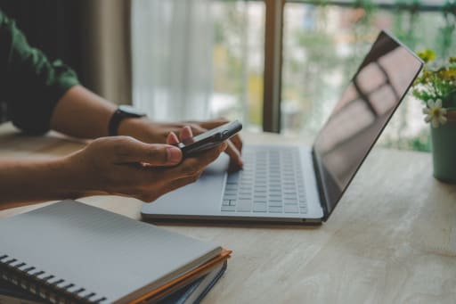Persona che utilizza pc e smartphone contemporaneamente Persona che utilizza pc e smartphone contemporaneamente