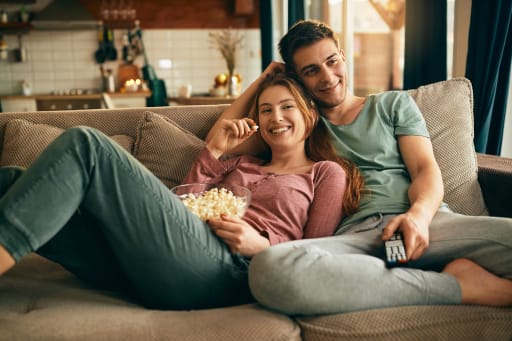coppia di ragazzi sul divano mangiano popcorn coppia di ragazzi sul divano mangiano popcorn