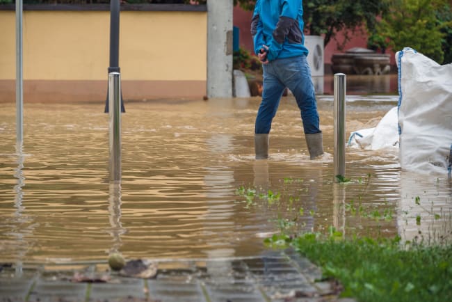 uomo che cammina in una strada allagata uomo che cammina in una strada allagata