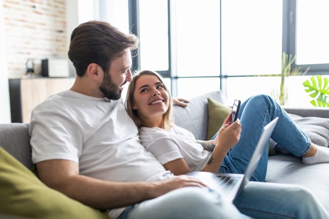 coppia su divano con smartphone e computer coppia su divano con smartphone e computer