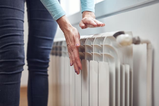 Donna che controlla la temperatura di un calorifero con le mani