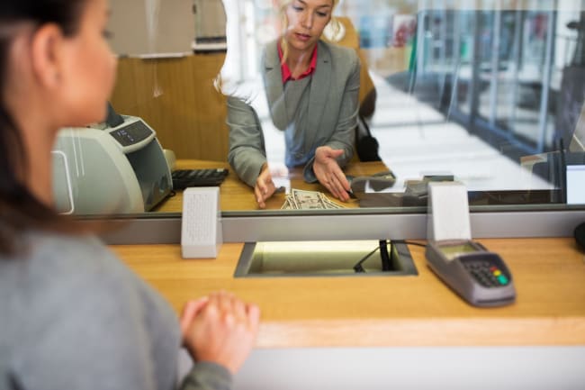 addetta-allo-sportello-bancario-serve-una-cliente addetta-allo-sportello-bancario-serve-una-cliente