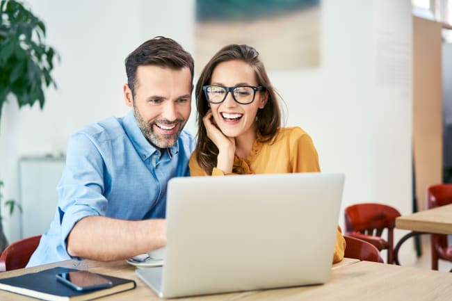 Coppia sorridente che valuta offerte online Coppia sorridente che valuta offerte online