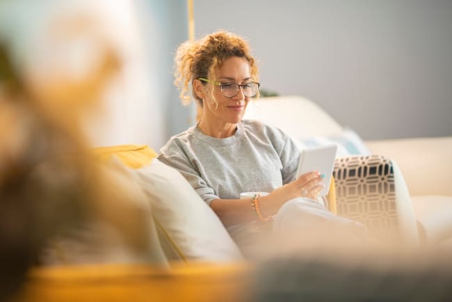 Donna a casa che legge su tablet Donna a casa che legge su tablet