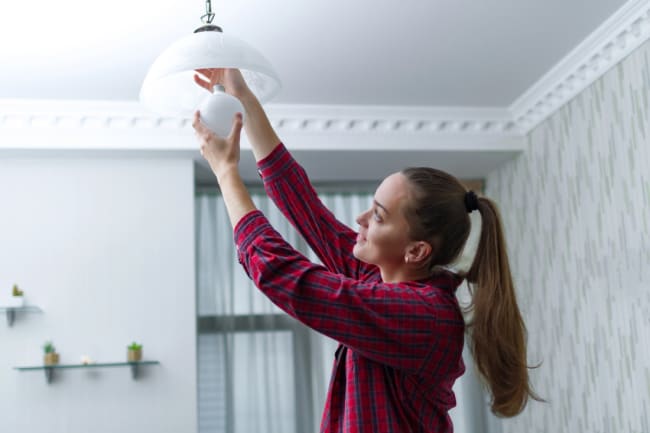 giovane donna sostituisce la lampadina LED giovane donna sostituisce la lampadina LED