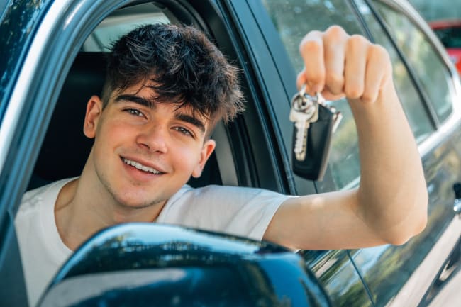 giovane ragazzo mostra le chiavi dell auto dal finestrino giovane ragazzo mostra le chiavi dell auto dal finestrino