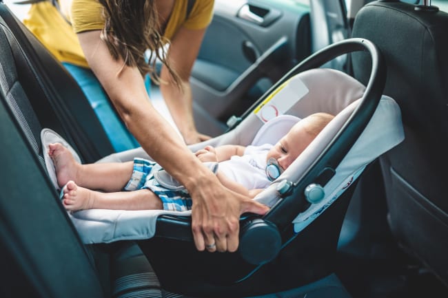 Mamma che sistema il seggiolino del proprio bambino in auto Mamma che sistema il seggiolino del proprio bambino in auto