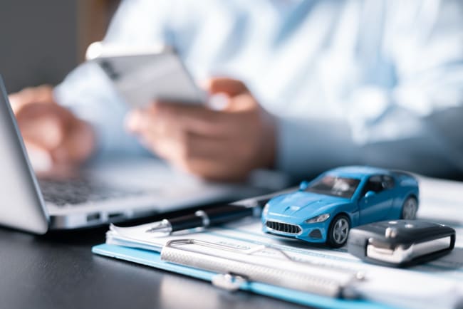 modellino e chiavi dell'auto con persona al pc e telefono modellino e chiavi dell'auto con persona al pc e telefono