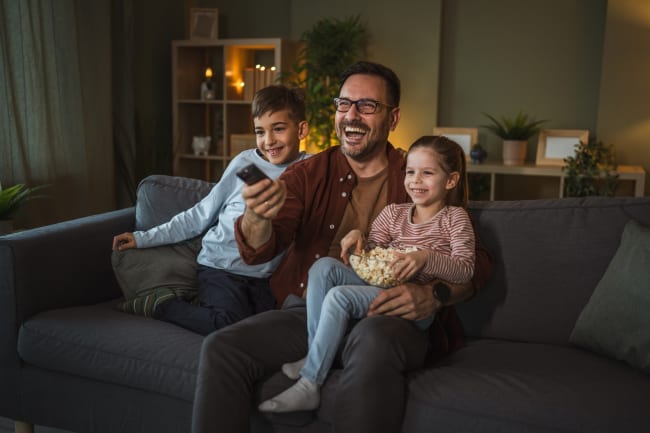 Papà con bambini che guardano tv