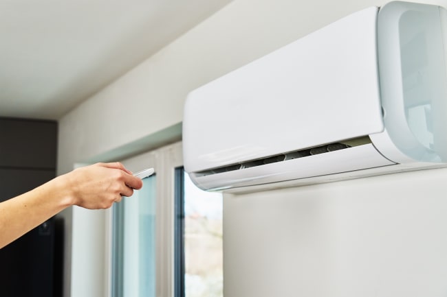 Persona che regola la temperatura del condizionatore con il telecomando Persona che regola la temperatura del condizionatore con il telecomando
