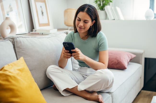 Ragazza che usa il cellulare seduta sul divano Ragazza che usa il cellulare seduta sul divano