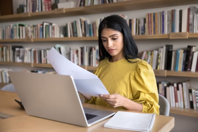 ragazza analizza fogli con computer davanti ragazza analizza fogli con computer davanti