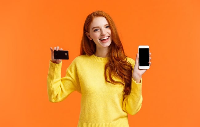 Ragazza con carta di credito e conto corrente e conto su smartphone arancione Ragazza con carta di credito e conto corrente e conto su smartphone arancione