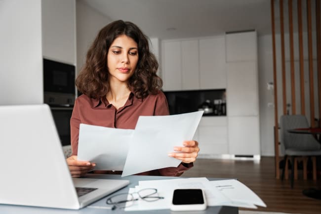 Ragazza che legge fogli e cerca offerte a pc