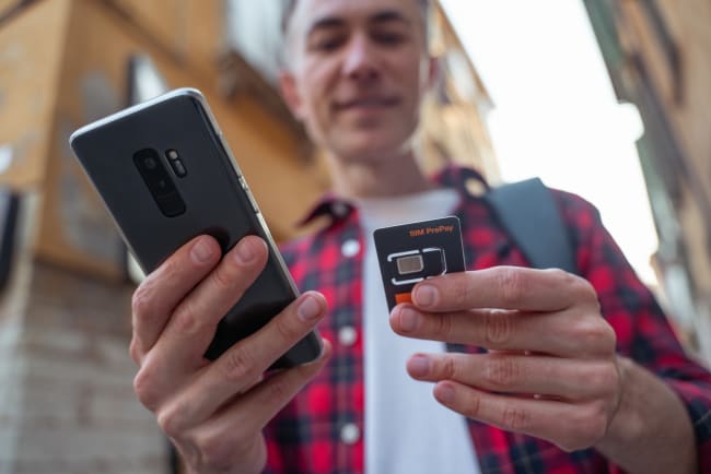 uomo con telefono e sim card in mano