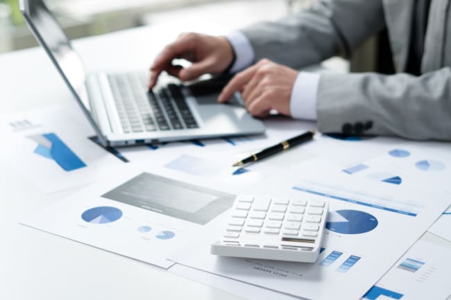 uomo usa la calcolatrice insieme al pc e fogli di lavoro uomo usa la calcolatrice insieme al pc e fogli di lavoro