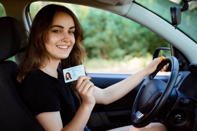 Ragazza alla guida con patente in mano Ragazza alla guida con patente in mano
