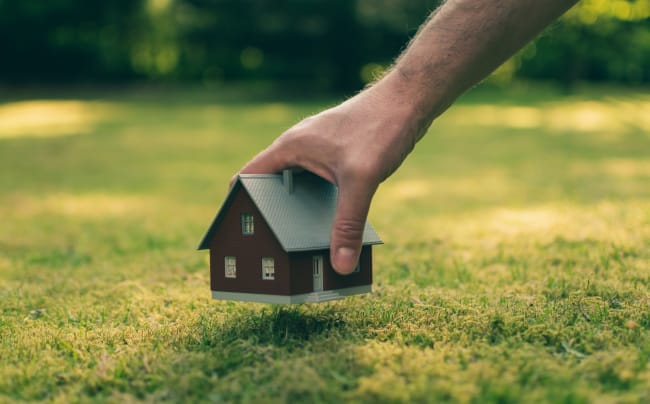 mano posa modellino di casa su prato