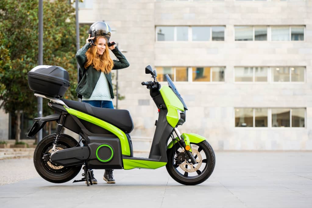 ragazza_si_mette_il_casco_per_salire_su_moto_elettrica ragazza_si_mette_il_casco_per_salire_su_moto_elettrica