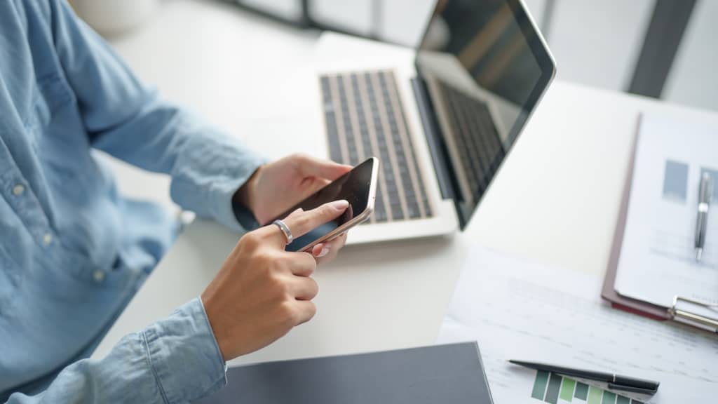 Persona che gestisce le finanze con pc e telefono Persona che gestisce le finanze con pc e telefono