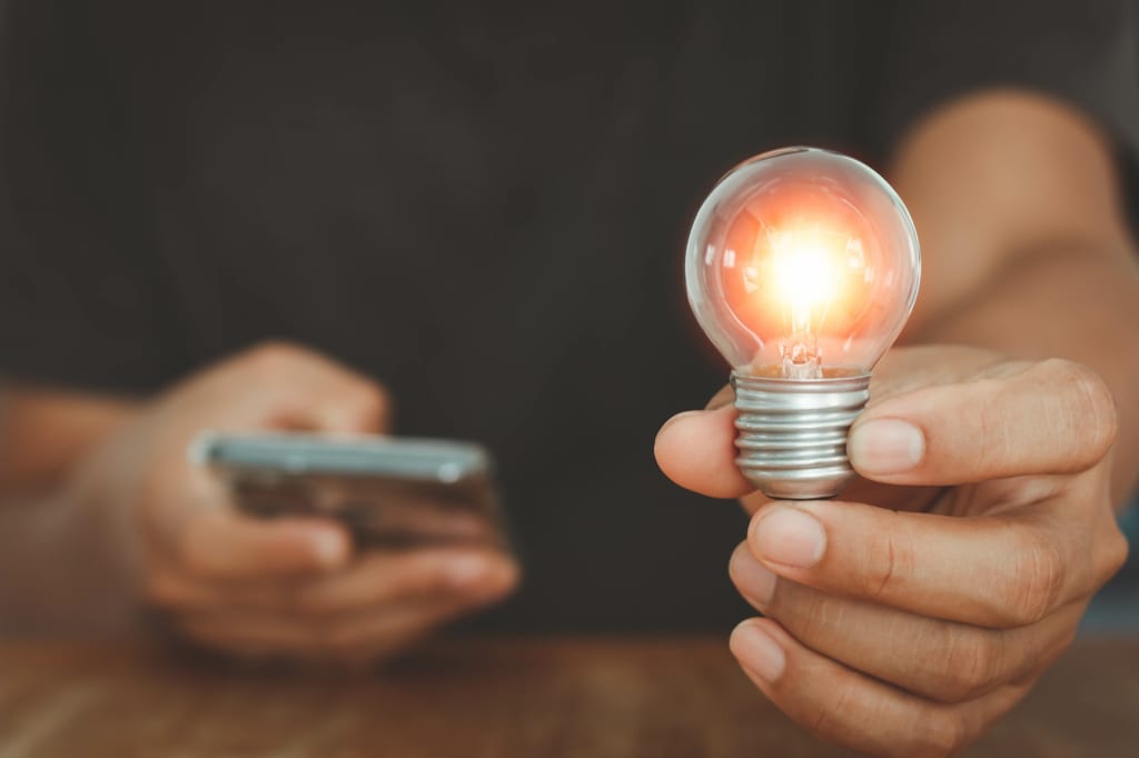 Uomo tiene in mano lampadina e cerca offerte Uomo tiene in mano lampadina e cerca offerte