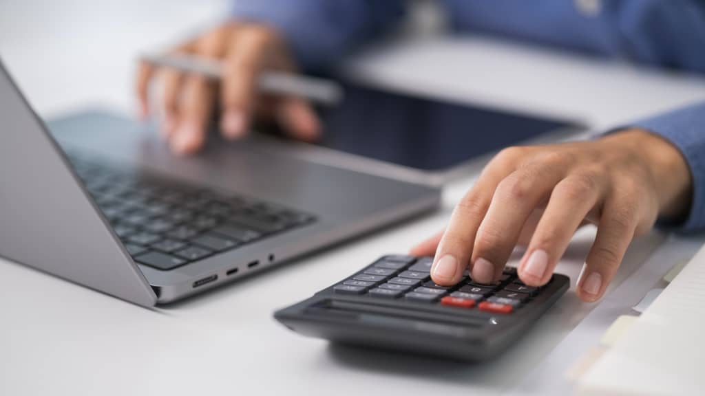 uomo digita su pc e calcolatrice