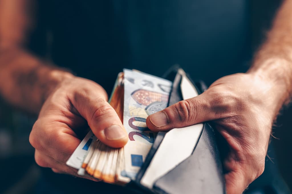 uomo che tiene in mano portafoglio con contanti