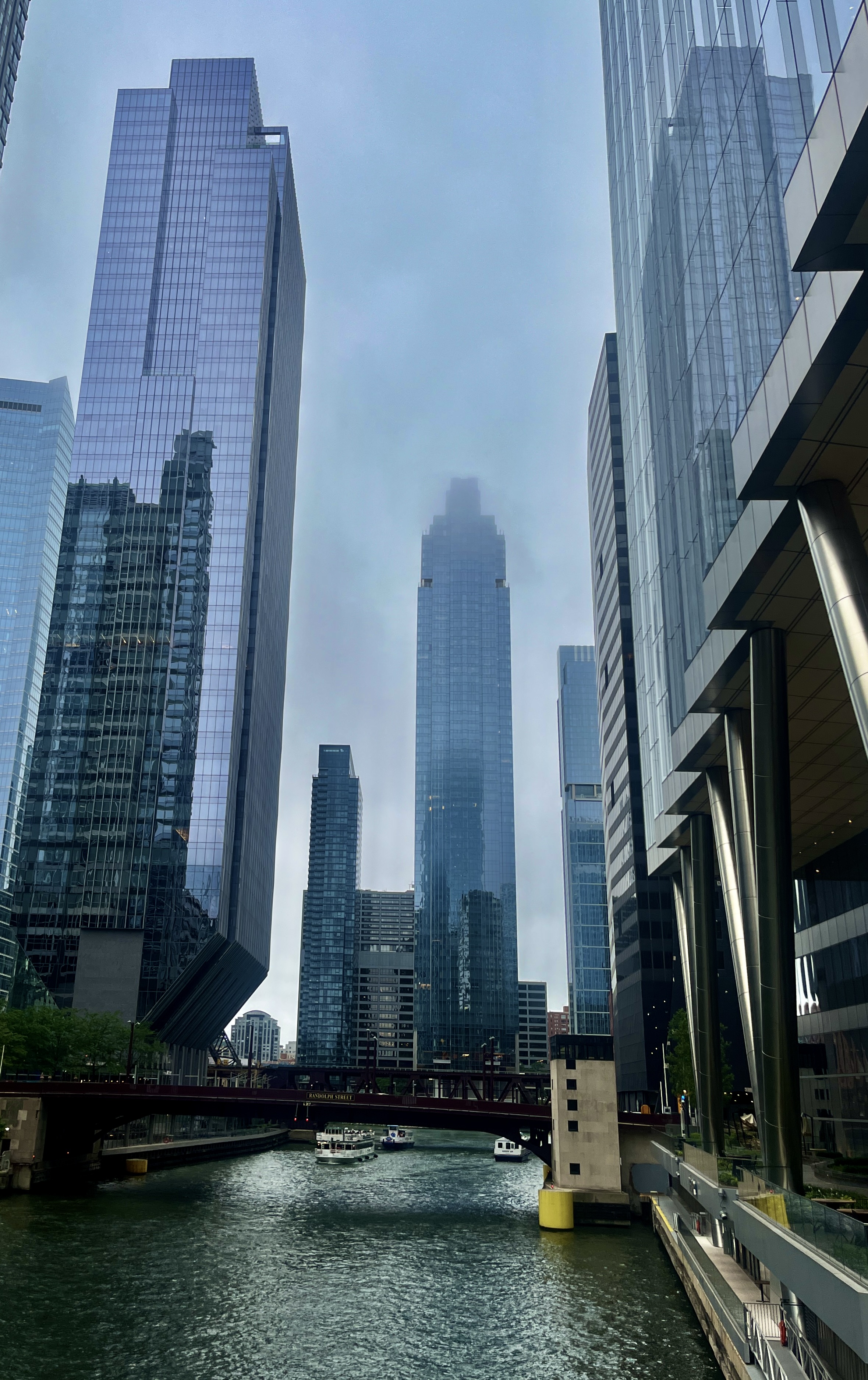 Street-level view with tall skyscrapers towering on both sides of the street under a clear blue sky