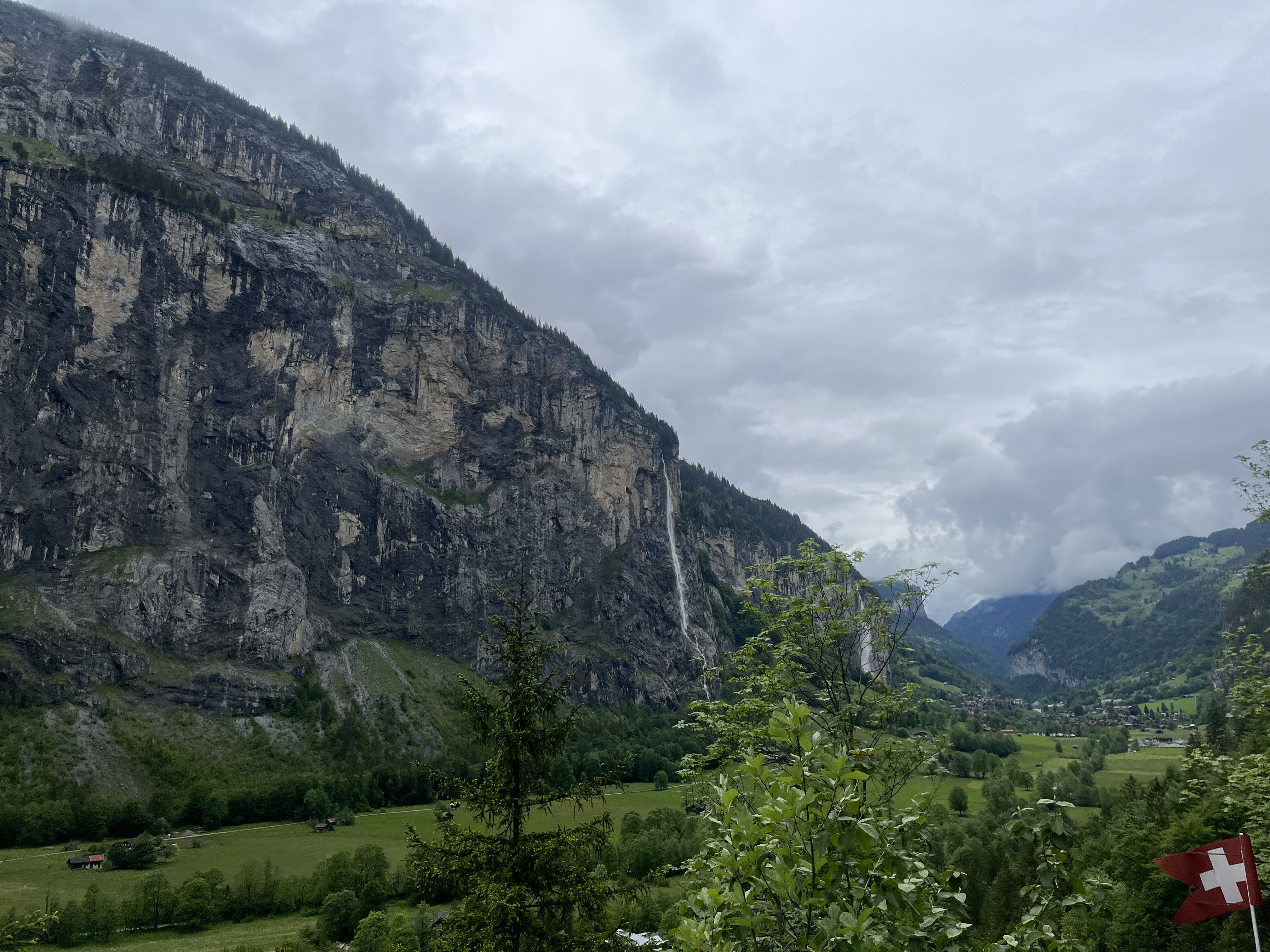 A view of a mountain, hills, and the Swiss Flag in Lauterbrunnen