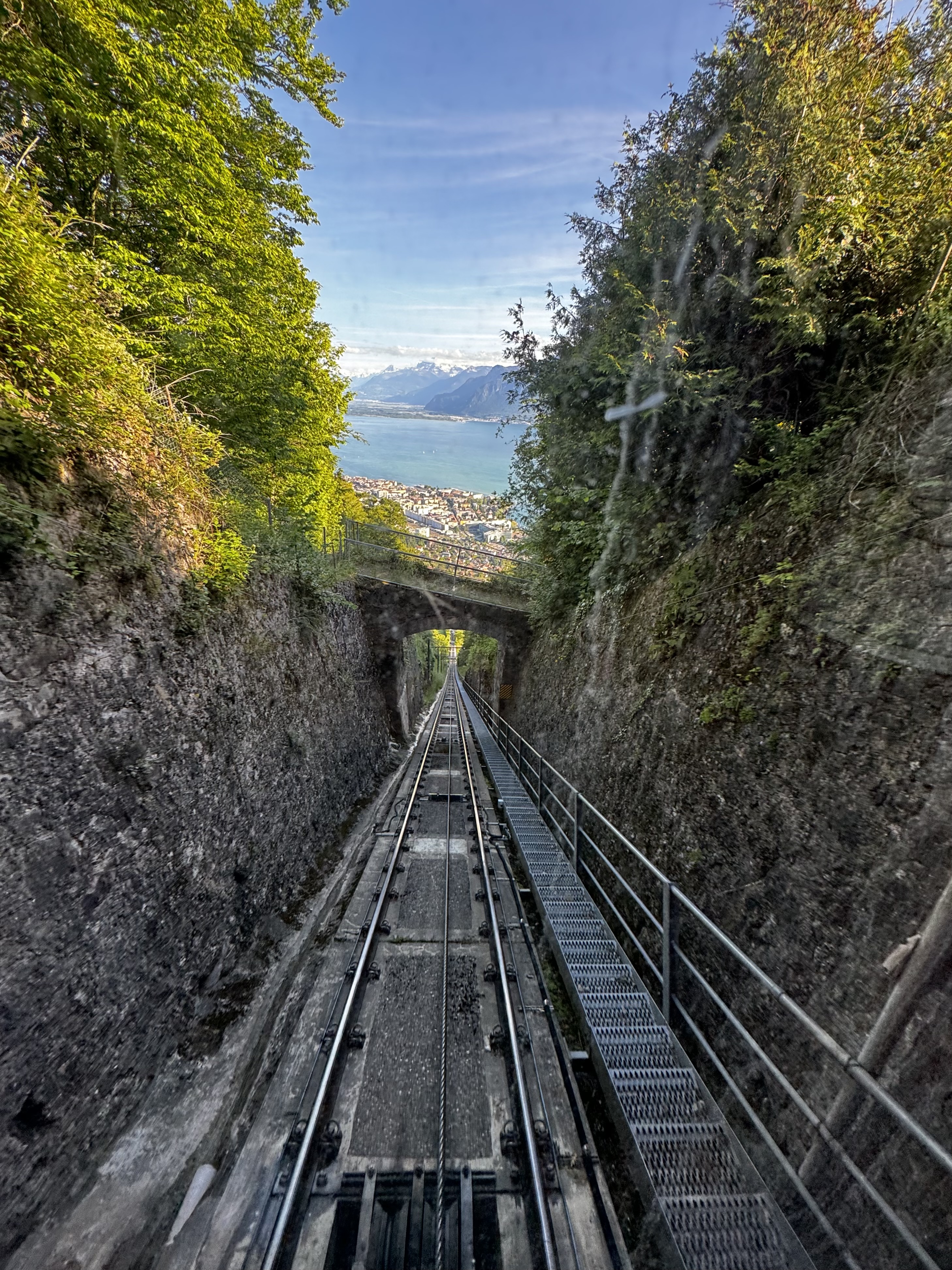 A view descending down train tracks with Lake Geneva in the background
