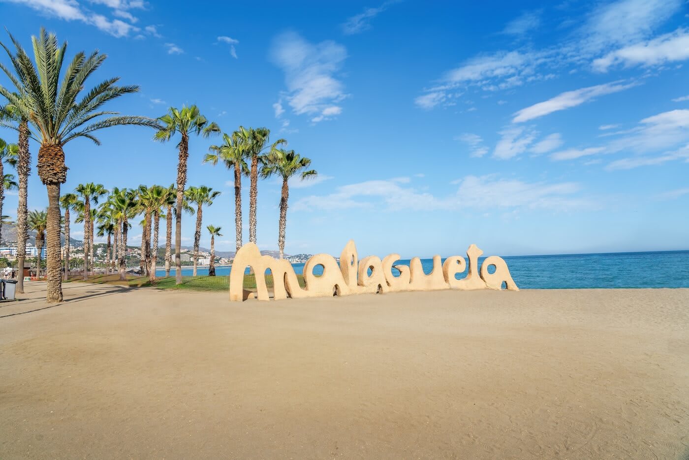 Sand palm trees and sign at Malaguete Beach Malaga