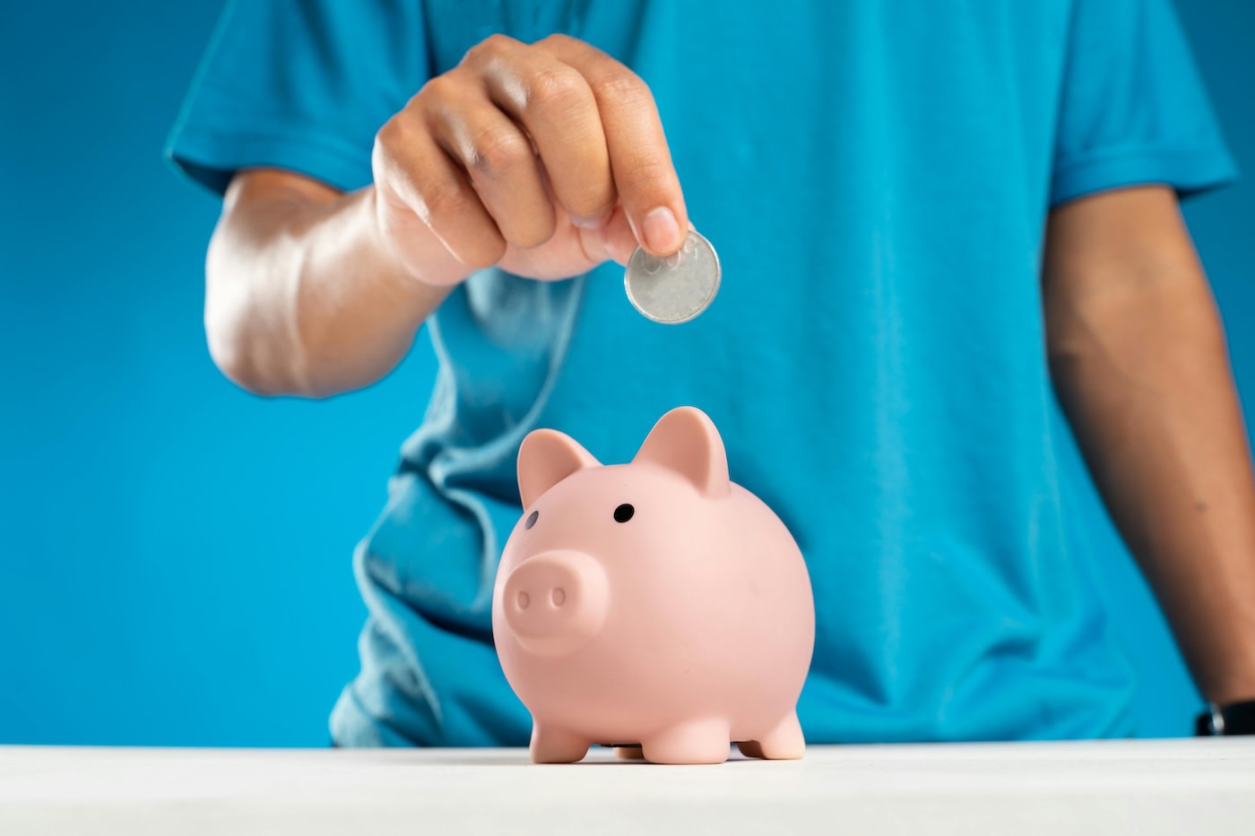 Person putting money into a piggy bank