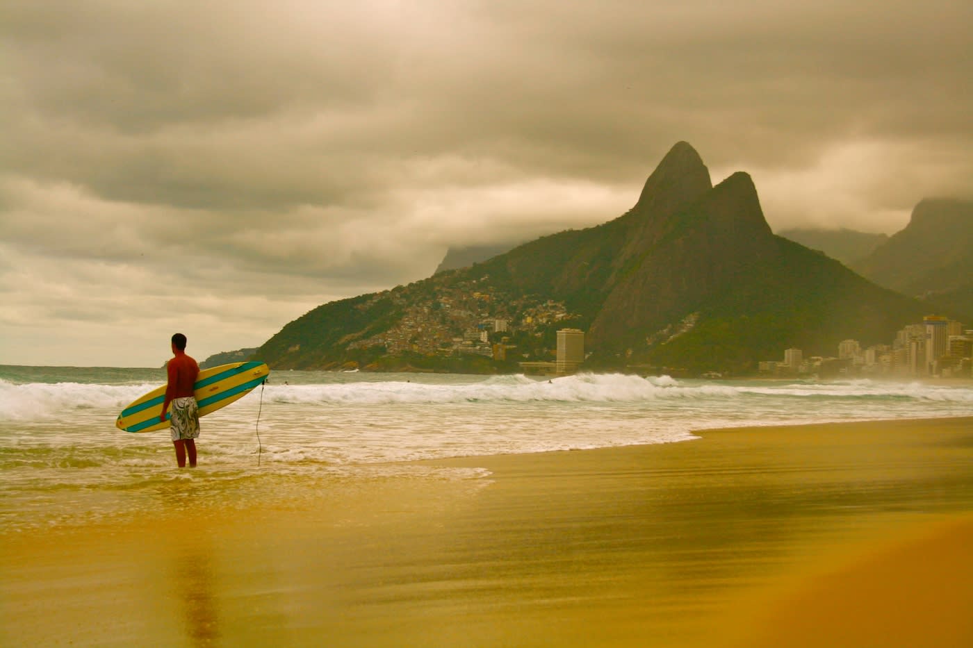 Surfer standing in the water with Rio behind him