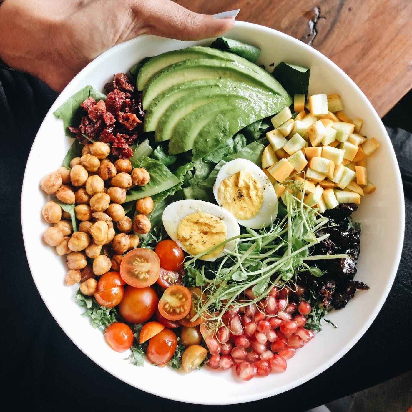 salad bowl with boiled egg, avocado, cherry tomatoes, chickpeas and greens