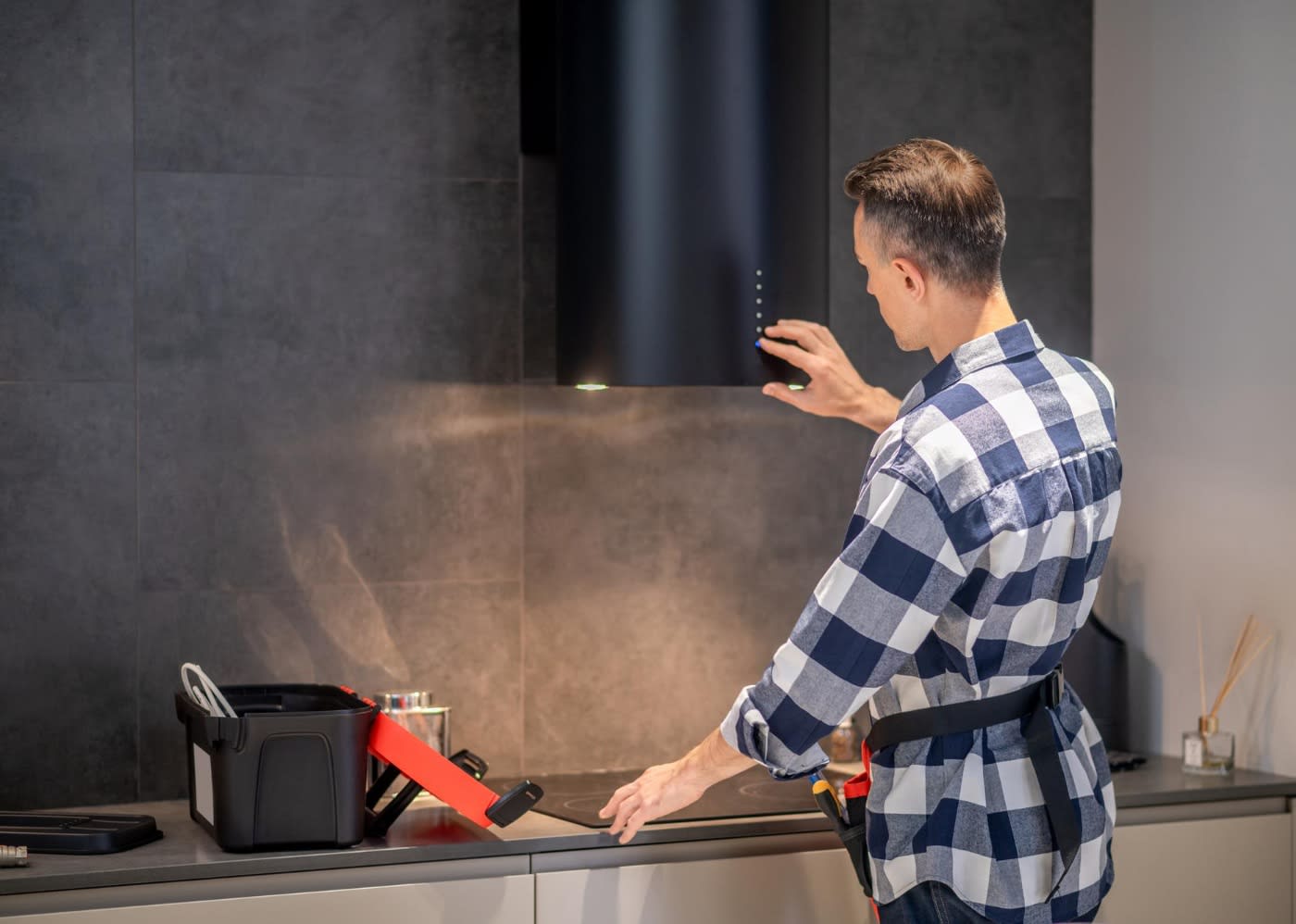 repair-man testing the cooker hood in a modern grey/black kitchen