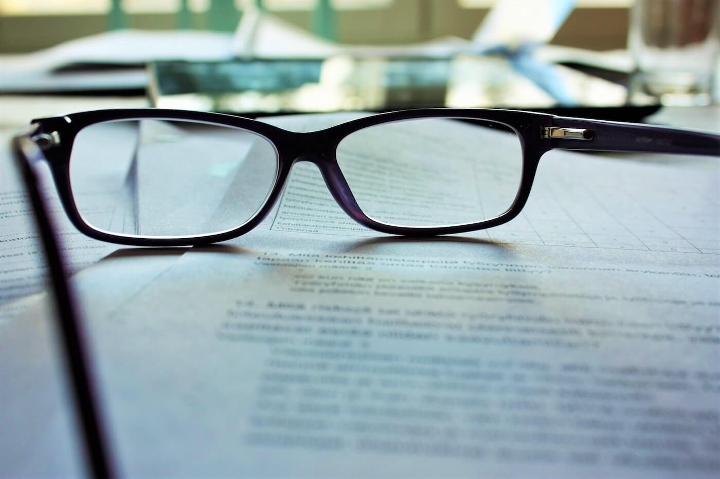 reading glasses sit on a stack of papers