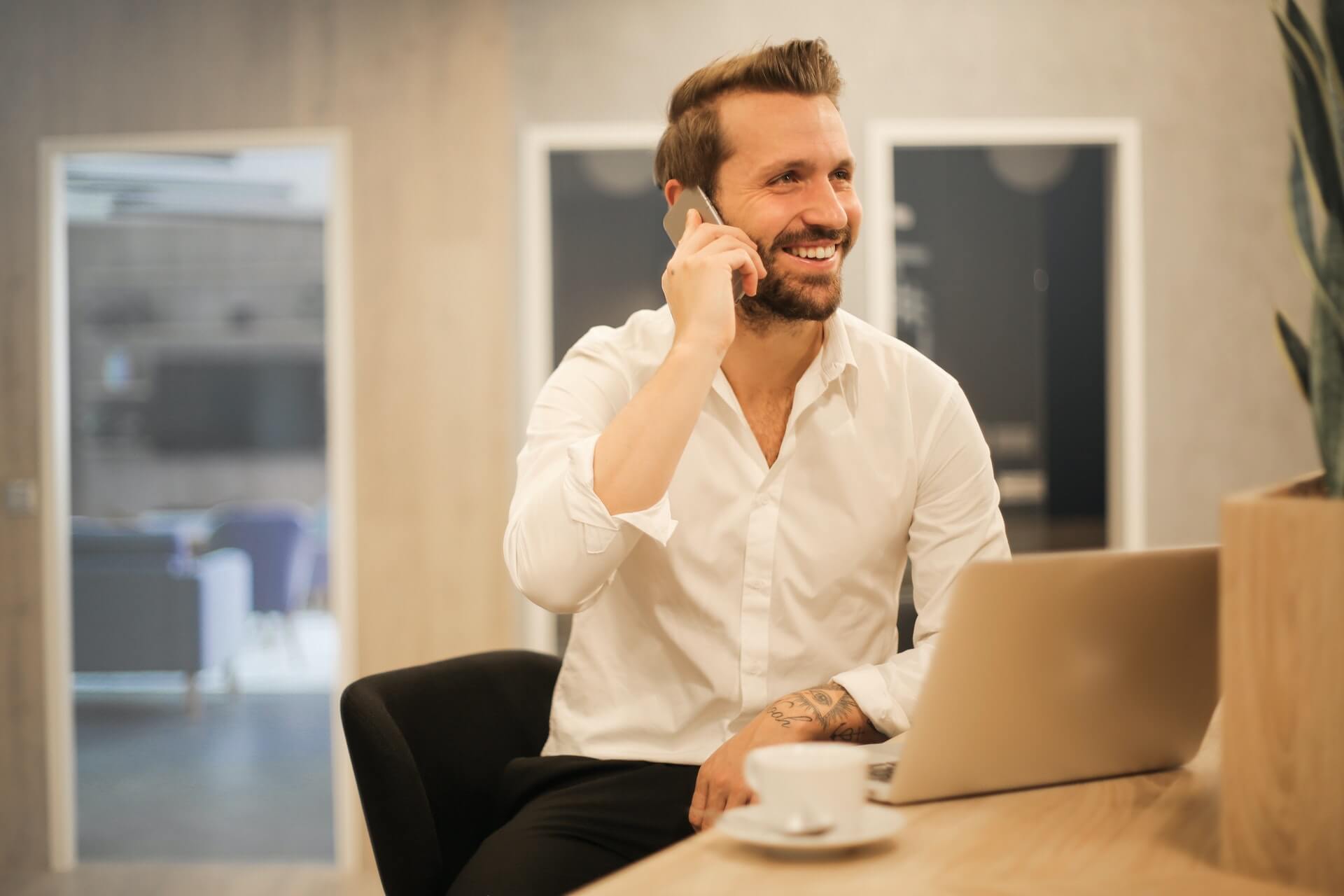 a happy tattooed man talks on a phone