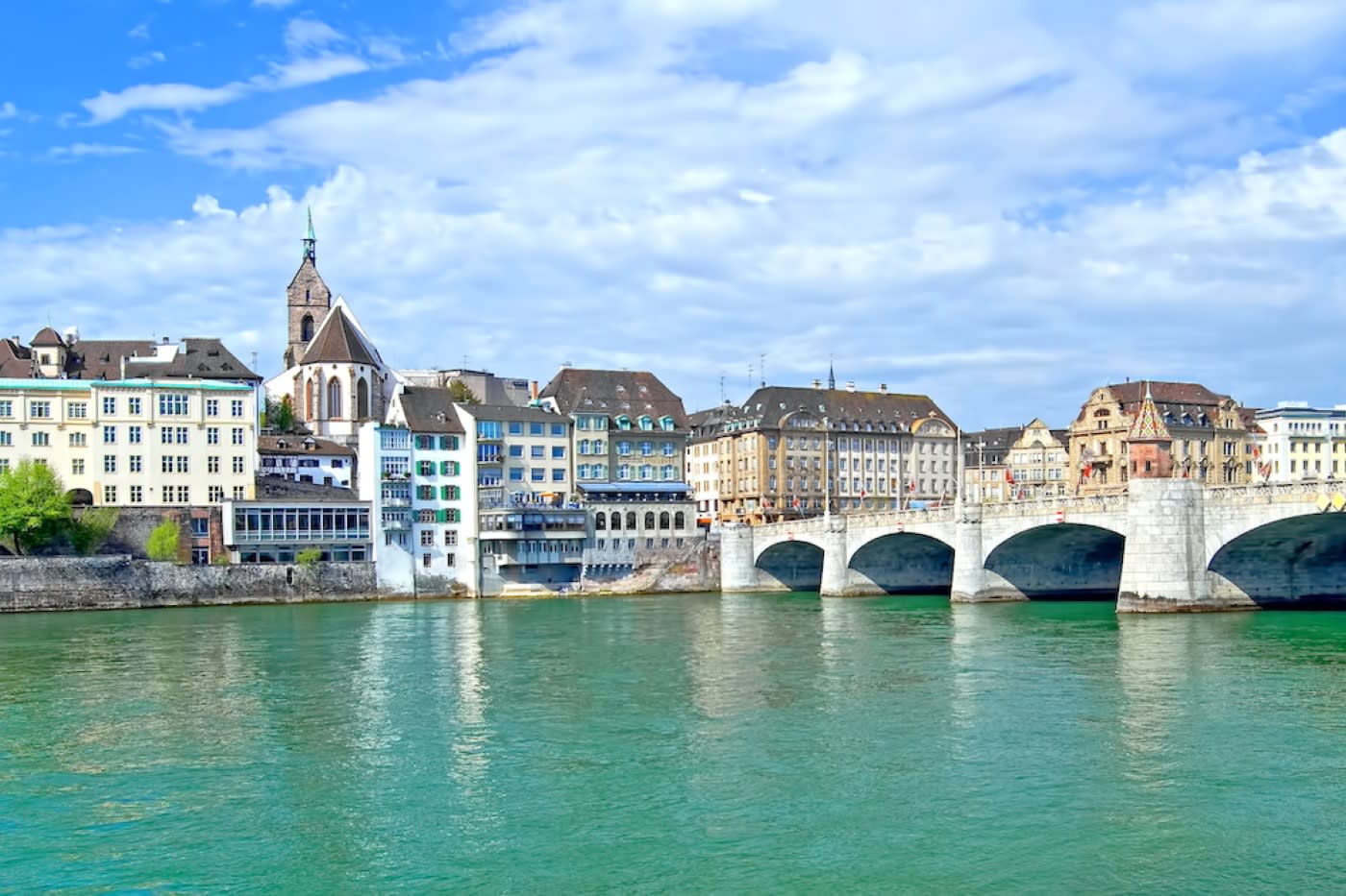A view of the river Rhine in Basel with a stone bridge and buildings.