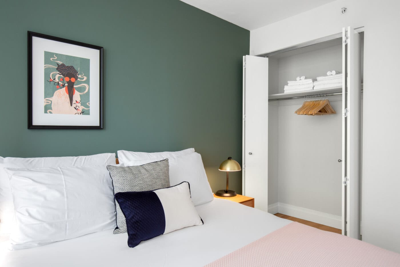 small bedroom with green accent wall and painting