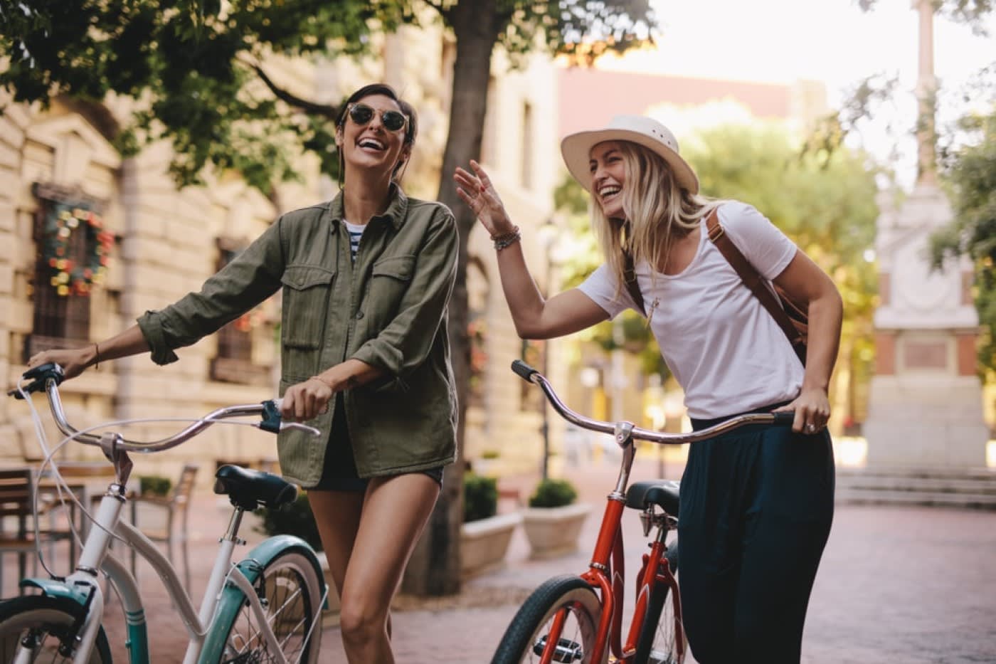 2 happy women walking on city street with bikes