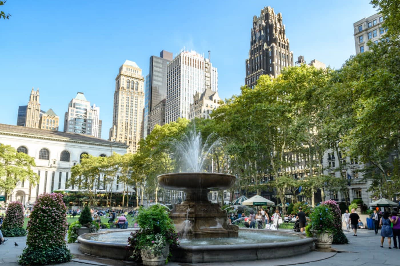 A large fountain in Bryant Park with greenery around