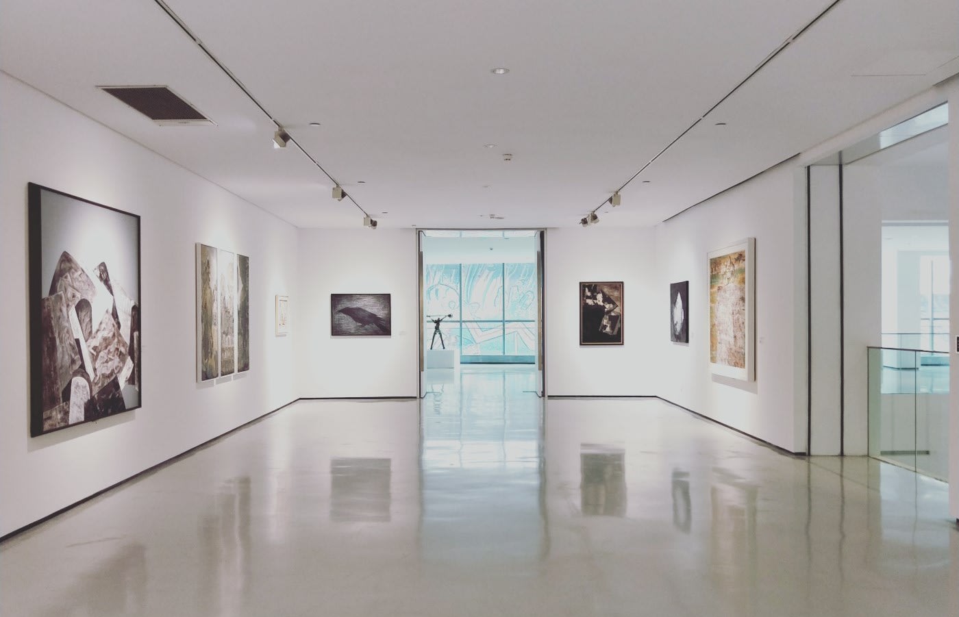 A square room in an art gallery with white walls and paintings