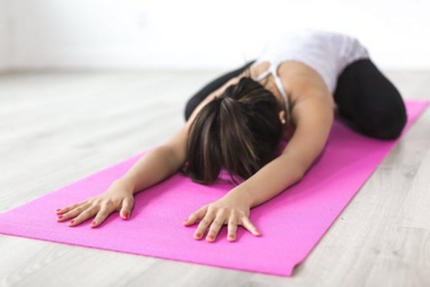 gyms in DC woman laying down on her yoga mat in child's pose during class