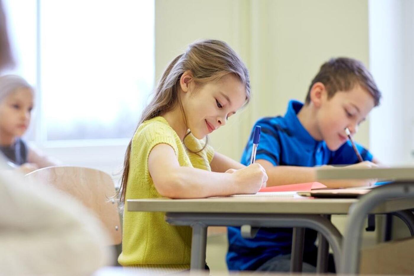 international schools Boston girl in yellow sitting next to boy in blue doing school work together